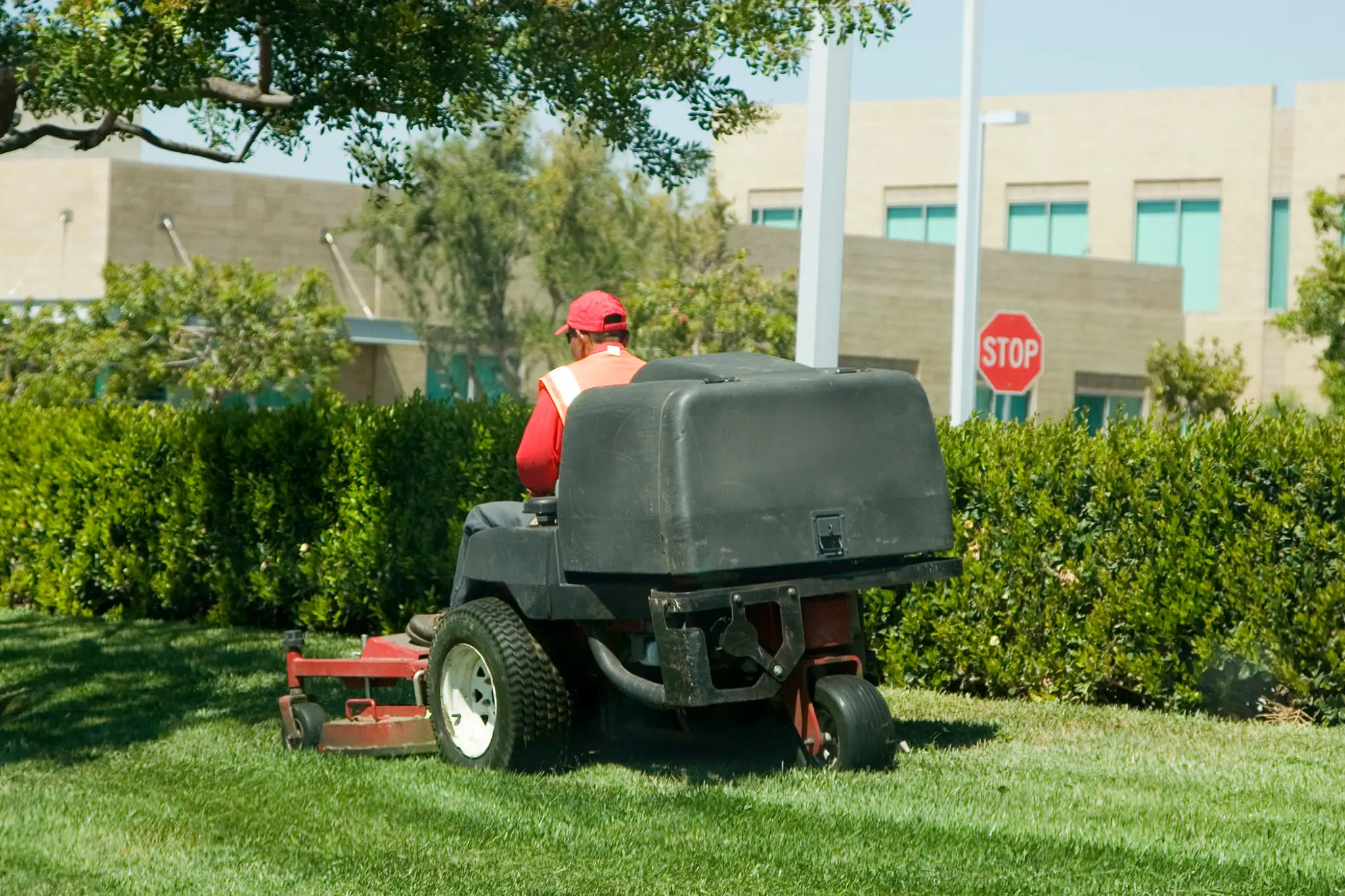 Person mowing lawn with riding mower.